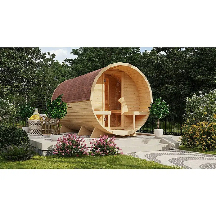 Karibu Fasssauna - L x B x H: 385 x 225 x 229 cm, 9 kW Bio-Saunaofen mit externer Steuerung, Anzahl Liegen: 4 Stk. - Außenaufnahme einer Fasssauna mit Holzverkleidung und gläserner Tür, umgeben von üppigem Grün. Die Fasssauna steht auf einer gepflasterten Fläche.