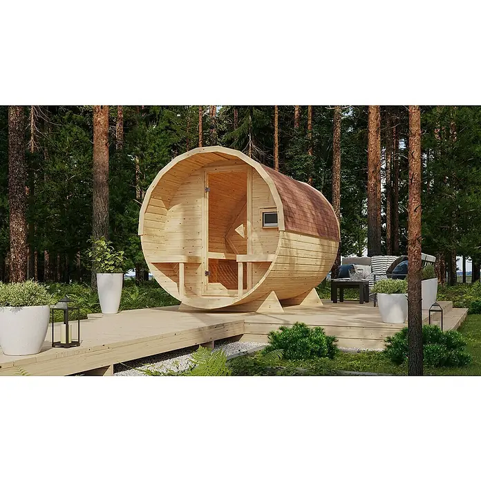 Karibu Fasssauna - L x B x H: 295 x 225 x 229 cm, 9 kW Saunaofen mit externer Steuerung, Anzahl Liegen: 2 Stk. - Ein Fass Sauna im Garten. Die Sauna ist aus hellem Holz gefertigt und steht auf einer Holzterrasse umgeben von Bäumen und Grünpflanzen.
