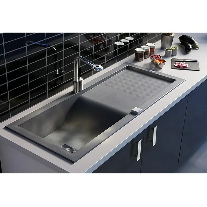 Carea Einbauspüle Vague - 118 x 50 cm, Schwarz, Material Spüle: CAREAgranit® - Nahaufnahme einer modernen Edelstahlspüle mit Abtropffläche, Armatur und frischen Zutaten auf einer Küchentheke.