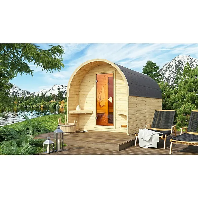 Karibu Fasssauna - L x B x H: 385 x 219 x 229 cm, Ohne Ofen - Abgebildet ist eine Fasssauna mit Außenbereich, Liegestühlen und Bergpanorama. Die Sauna bietet Entspannung pur in der Natur.