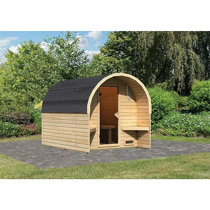 Karibu Fasssauna - L x B x H: 295 x 219 x 229 cm, Ohne Ofen - Ein Fassförmige Sauna aus hellem Holz mit dunklem Dach steht im Garten. Die Sauna hat eine Bank vor dem Eingang.