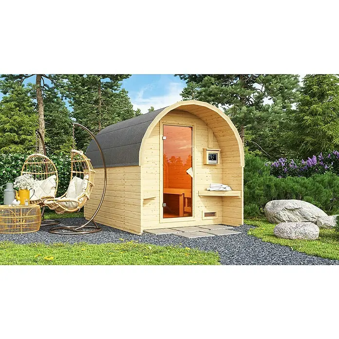 Karibu Fasssauna - L x B x H: 295 x 219 x 229 cm, 9 kW Saunaofen mit externer Steuerung - Bild einer Fasssauna mit Glastür und Holzeinrichtung im Garten, neben einem Hängesessel und umgeben von Bäumen und Pflanzen.