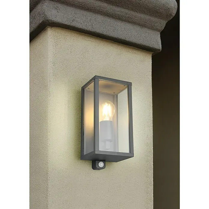Trio Leuchten Garonne Außenwandleuchte - 60 W, L x B x H: 13,5 x 14 x 29 cm, Anthrazit, IP44, Mit Bewegungsmelder - Eine moderne Außenleuchte mit Bewegungsmelder, die an einer Wand montiert ist und ein warmes, einladendes Licht ausstrahlt.