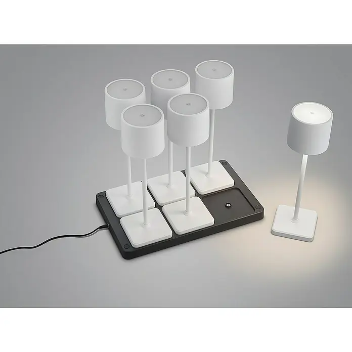 Reality Leuchten Akku-Tischleuchte FERNANDEZ + Ladestation - 6 W, L x B x H: 26 x 42,6 x 40 cm, Weiß, Mehrfarbig - Das Bild zeigt sechs weiße Tischleuchten, die auf einer schwarzen Ladestation stehen, wobei eine Leuchte separat platziert ist. Elegantes Beleuchtungsset.