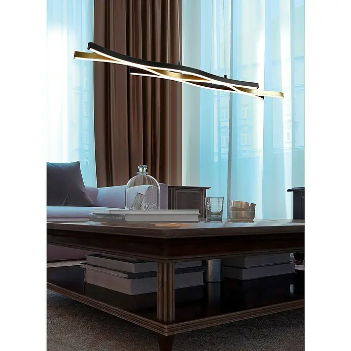Trio Leuchten Blaze LED-Pendelleuchte - 35 W, L x B x H: 15,5 x 107,5 x 150 cm, Messing matt/Schwarz, Mehrfarbig - Eine moderne, mehrfarbige Hängeleuchte mit geschwungenen Linien hängt elegant über einem Wohnzimmertisch. Stilvolle Beleuchtung für Ihr Zuhause.