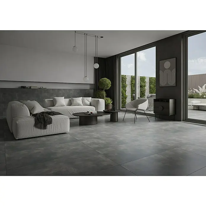 Feinsteinzeugfliese Big Show XXL - 59,8 x 119,8 cm, Grafit, Matt - Modernes Wohnzimmer mit grauen Fliesen, einem weißen Sofa und einem stilvollen Sessel. Die grauen Fliesen bilden einen eleganten Kontrast zu den hellen Möbeln.