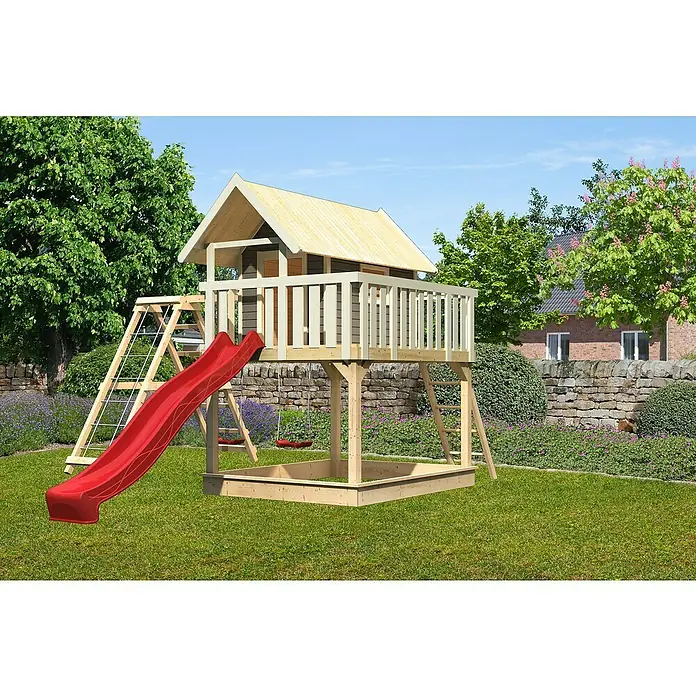 Karibu Kinderspielturm Fidel - L x B x H: 243 x 198 x 329,5 cm, Terragrau, Mit roter Rutsche & Klettergerüst - Dieses Bild zeigt ein hölzernes Spielhaus mit Rutsche und Sandkasten im Garten. Das Spielhaus verfügt über eine Leiter und einen Kletterbereich.