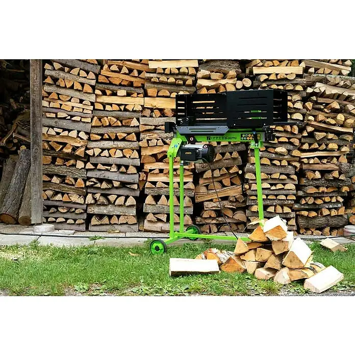 Zipper Holzspalter ZI-HS7TU - 2.300 W, 7 t, Max. Spaltgutlänge: 52 cm - Brennholzspalter vor einem Holzstapel. Die Maschine in Grün und Schwarz spaltet Holz, das im Hintergrund gestapelt ist.