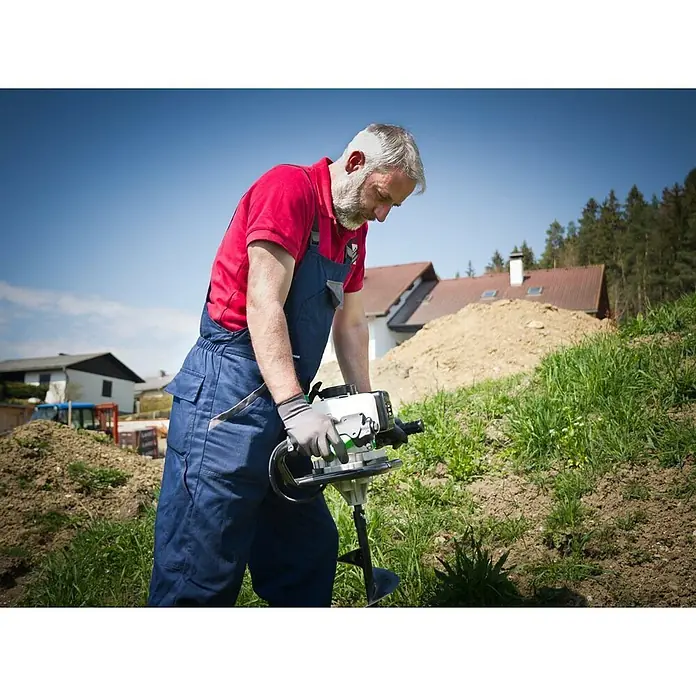Zipper Erdbohrer ZI-ELB70 - 100 mm, Geeignet für: Erde - Ein Mann bedient einen Erdbohrer im Freien, um Löcher zu bohren. Ideal für Gartenarbeiten und Bauprojekte.