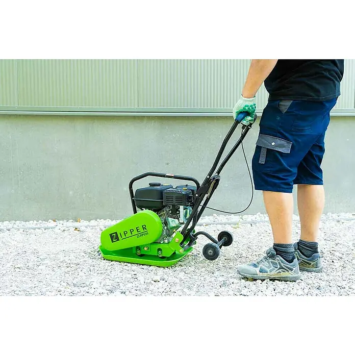 Zipper Rüttelplatte ZI-RPE60 - Motorleistung: 4.100 W, 3,6 l - Ein grüner Zipper ZI-RPE60 Vibrationsstampfer steht auf Kies, bedient von einer Person mit Handschuhen und blauen Shorts für Bodenverdichtung.