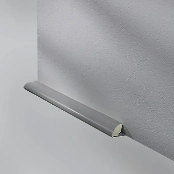 LOGOCLIC Viertelstab Grau - 250 cm x 14 mm x 14 mm - Nahaufnahme einer Viertelkreis-Sockelleiste in Grau an einer Wand, die den Übergang zwischen Wand und Boden elegant betont.