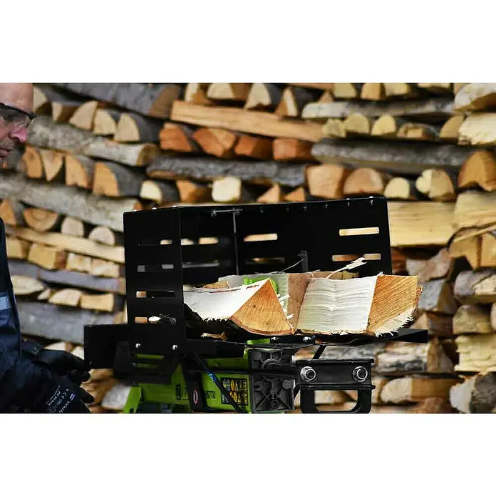 Zipper Holzspalter ZI-HS7TU - 2.300 W, 7 t, Max. Spaltgutlänge: 52 cm - Holzspalter in Aktion vor einem Holzhintergrund. Das Gerät ist grün und schwarz und spaltet Holzscheite.