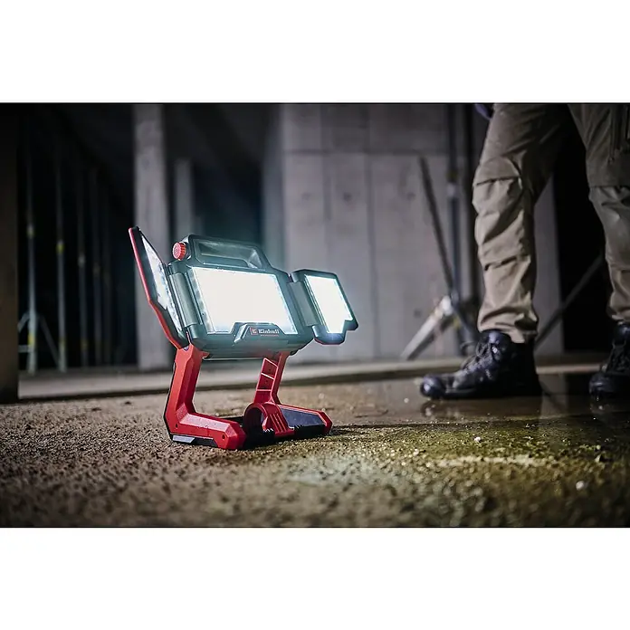Einhell Professional Power X-Change 18V LED Baustrahler TP-CL 18/3000 Li-Solo - 18 V, Ohne Akku, 3.000 lm, 5.700 K - Einhell Akku-LED-Strahler mit roter Halterung beleuchtet eine Baustelle, ideal für Handwerker, die helles, kabelloses Licht benötigen.