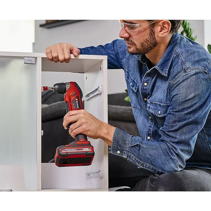 Einhell Power X-Change 18V Akku-Winkelbohrmaschine TE-AD 18 Li-Solo - 18 V, Ohne Akku, 1.100 U/min - Ein Mann montiert mit einem Einhell Akku-Winkelschrauber Möbel, wobei der Fokus auf dem Werkzeug und dessen Anwendung liegt.