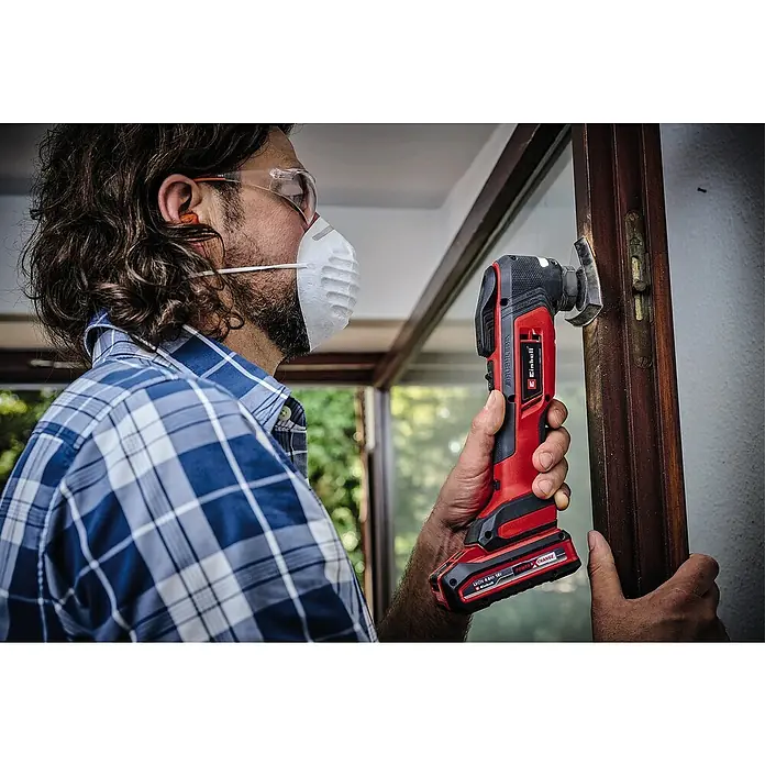 Einhell Professional Power X-Change 18V Akku-Multifunktionswerkzeug TP-MG 18 Li BL-Solo - 18 V, Ohne Akku, Oszillationswinkel: 3,2 ° - Ein Mann benutzt ein Einhell Multifunktionswerkzeug zum Renovieren. Das Akku-Werkzeug ist rot/schwarz und wird zum Schleifen verwendet.