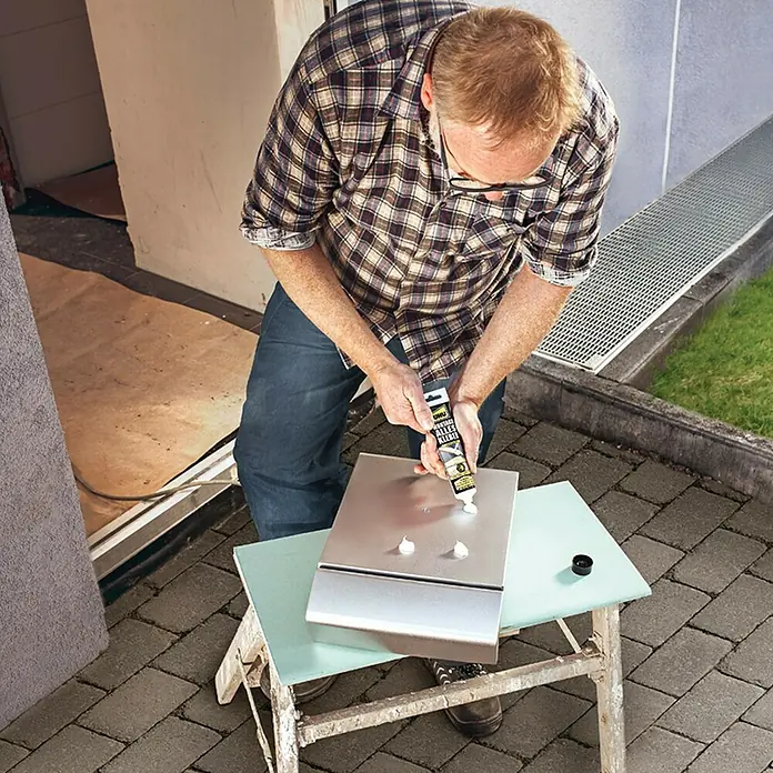 UHU Montagekleber Alleskleber - 165 g, Tube - Ein Mann, der mit einem UNU Alleskleber-Produkt zwei Teile zusammenklebt. Das Produkt ist ein hochwertiger Klebstoff für vielfältige Anwendungen.