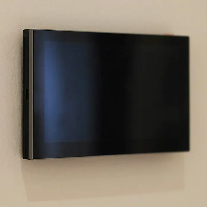 EZVIZ Türsprechanlagen-Monitor SD7 - Auflösung: 1.024 x 600 Pixel, Silber/Schwarz, 180,3 × 111,6 × 15,6 mm - Nahaufnahme eines an einer Wand montierten schwarzen Touchscreen-Displays mit schlankem Rahmen und reflektierender Oberfläche.