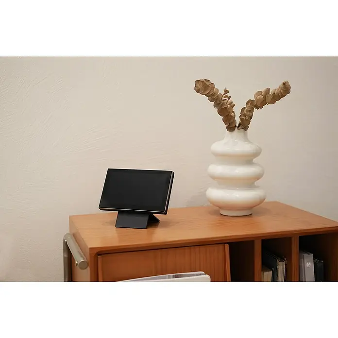 EZVIZ Türsprechanlagen-Monitor SD7 - Auflösung: 1.024 x 600 Pixel, Silber/Schwarz, 180,3 × 111,6 × 15,6 mm - Nahaufnahme eines minimalistischen Smart Displays mit schlankem Design und Touchscreen, das auf einem Holzmöbelstück neben einer dekorativen Vase steht.