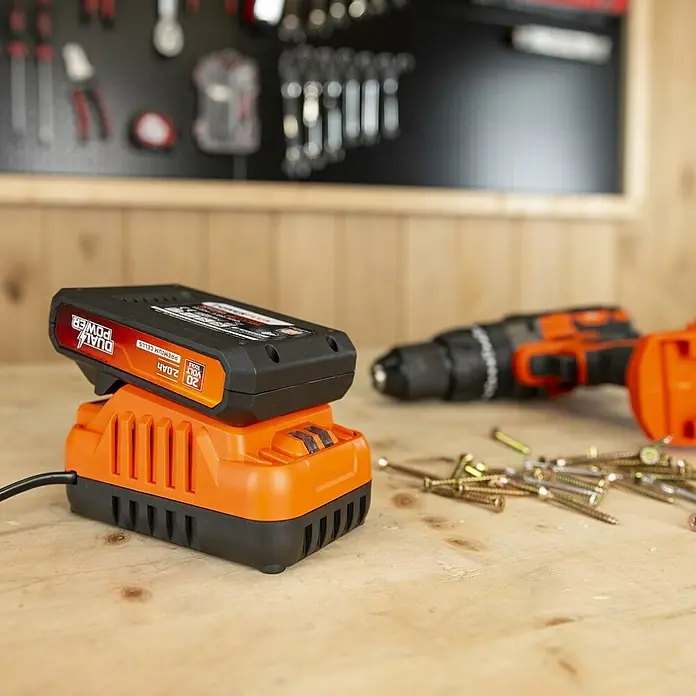PowerPlus Batería y cargador POWDP90620 - 20 V, 1 batería, 2 Ah - Primer plano de una batería Dual Power en un cargador. La batería es negra y naranja y tiene una capacidad de 2,0 Ah.
