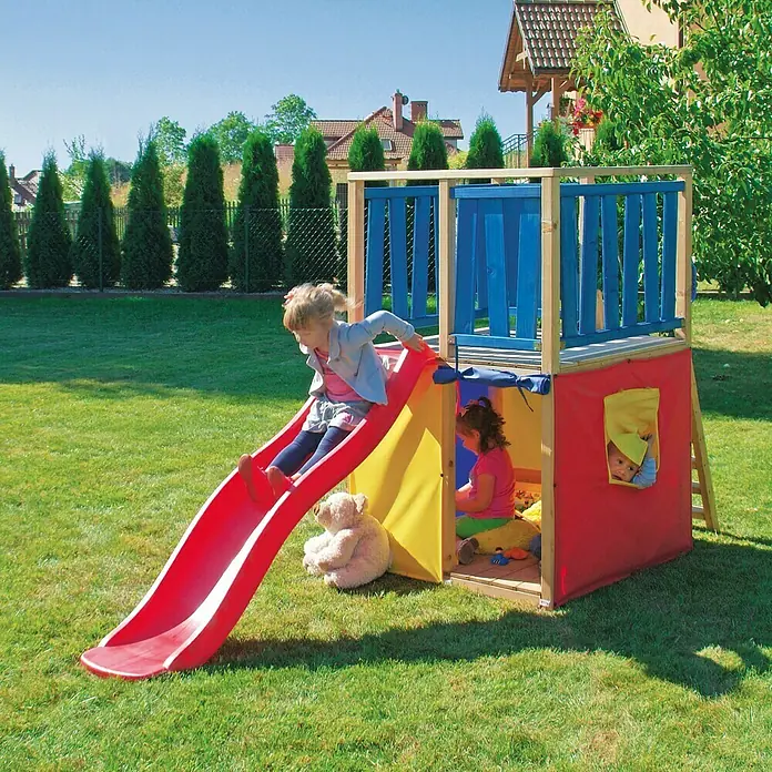 Kinderspielturm Funny - L x B x H: 140 x 100 x 160 cm - Kinder spielen mit einem bunten Spielturm mit Rutsche im Garten. Der Turm hat eine rote Rutsche und ist mit Stoff in verschiedenen Farben verkleidet.