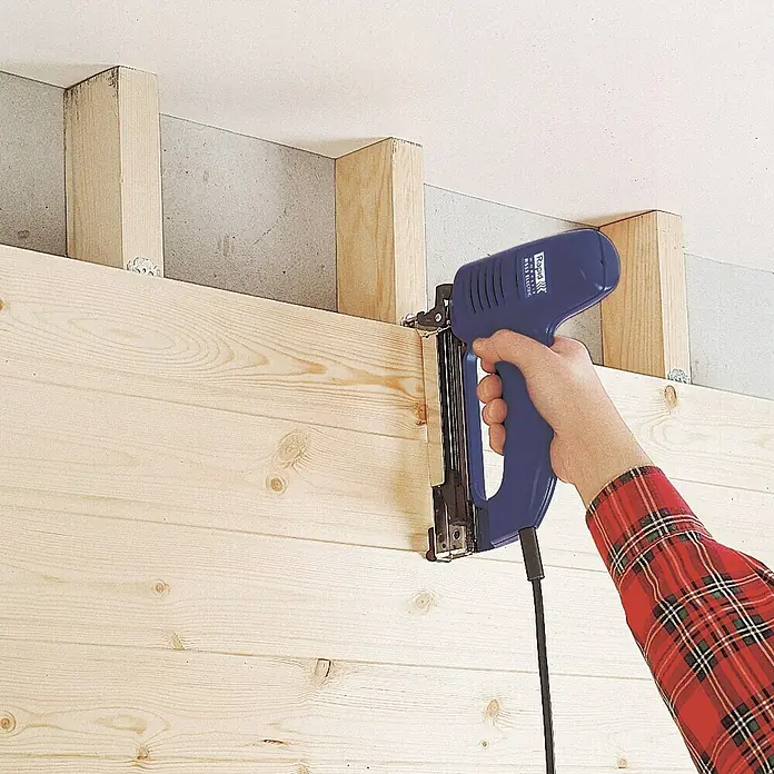 Rapid Kombi-Elektrotacker R553 PRO - Klammertiefe: 8 mm - 20 mm, Elektrisch, Schachtel - Elektro-Tacker beim Befestigen von Holzpaneelen an einer Wand. Das blaue Werkzeug ist perfekt für Heimwerkerprojekte.