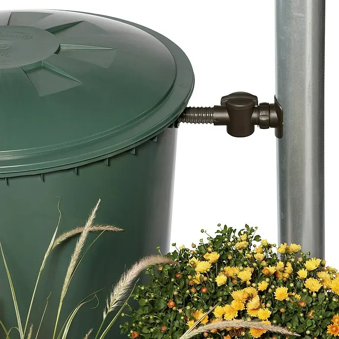 Garantia Regensammler mit Filtereinsatz Speedy - Geeignet für: Fallrohrgrößen DN 70 - 100 - Nahaufnahme einer grünen Regentonne mit montiertem Auslaufhahn und Blumen im Vordergrund, ideal für Gartenbewässerung.
