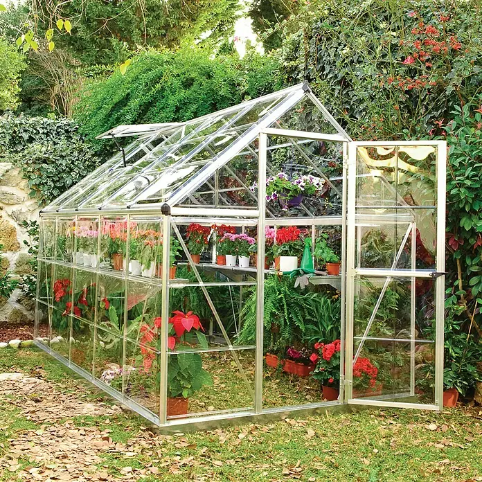 Palram – Canopia Invernadero Harmony - Medidas ext. (An x Pr): 185 x 306 cm, Plateado, Área: 5,6 m² - Invernadero con puerta abierta, lleno de plantas vibrantes, que ofrece un entorno ideal para el cultivo.