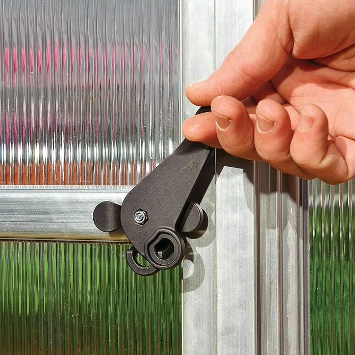 Palram – Canopia Gewächshaus Bella - Außenmaß inkl. Dachüberstand (B x T): 244 x 367 cm, 6 mm, Silber - Nahaufnahme eines schwarzen Drehriegelverschlusses an einer Gewächshaustür, bedient von einer Hand. Präzise Detailaufnahme der Verschlussmechanik.
