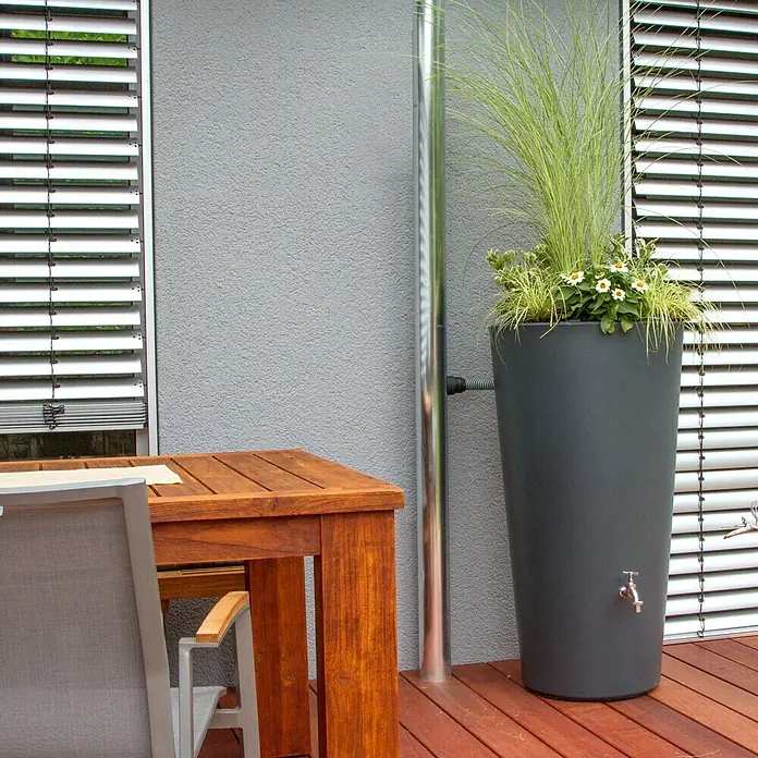 Regenspeicher Rainbowl Flower - 150 l, Anthrazit - Nahaufnahme eines stilvollen, grauen Regenspeichers mit Bepflanzung, der sich harmonisch in eine moderne Terrasse einfügt.