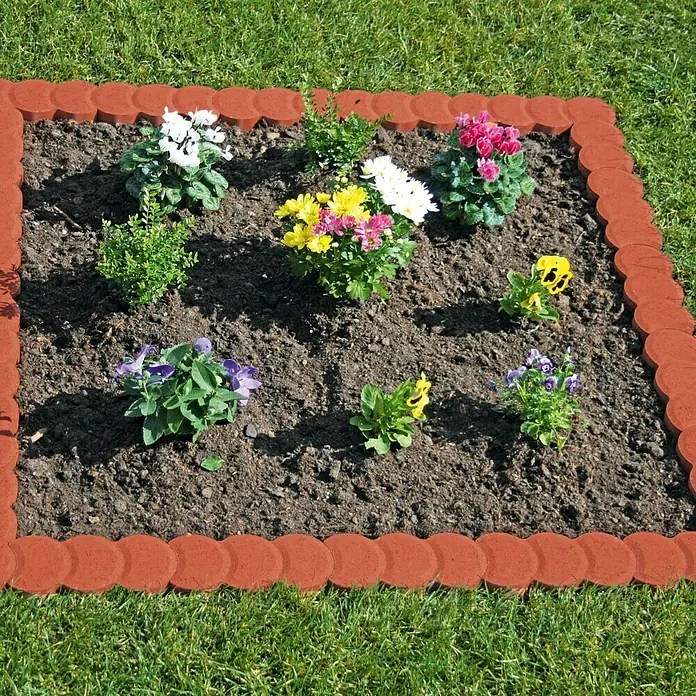 Christoph Mähstein Pali - 22 x 10 x 4,2 cm, Toskana, Beton - Ein quadratisches Blumenbeet mit roten Randsteinen, gefüllt mit Erde und einer Auswahl an bunten Frühlingsblumen, umgeben von grünem Gras.