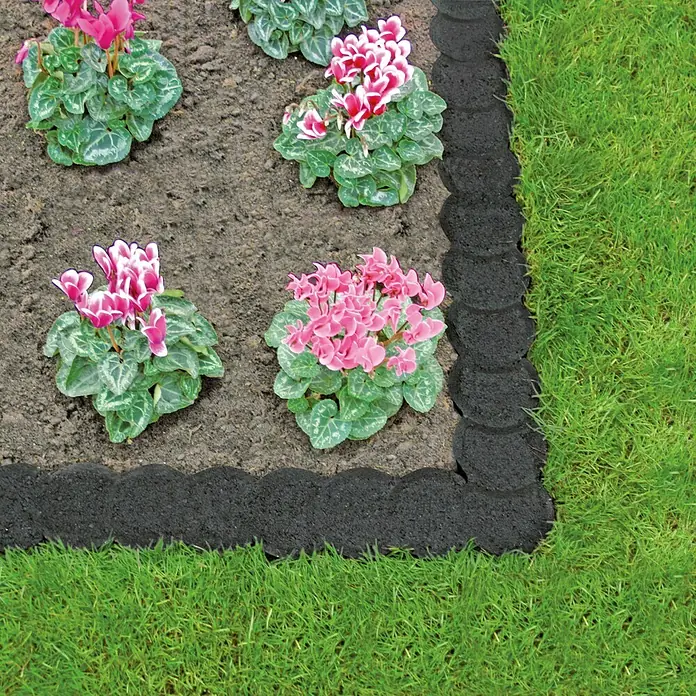 Christoph Mähstein Pali - 22 x 10 x 4,2 cm, Anthrazit, Beton - Bild einer Beetumrandung aus recyceltem Gummi, die ein Blumenbeet mit rosa und weißen Blüten von einem grünen Rasen trennt.