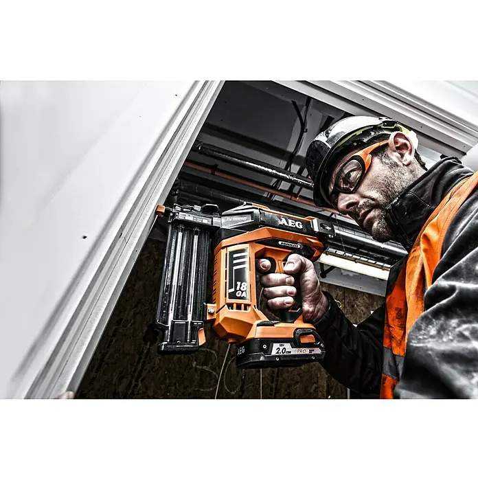 AEG Pro 18V Akku-Nagler B18N18-0 - 18 V, Li-Ionen, Ohne Akku, Länge Nagel: 15,9 mm - 55 mm - Ein Handwerker benutzt einen AEG Akku-Nagler. Das kabellose Gerät ist orange und schwarz und wird für Bauarbeiten verwendet.