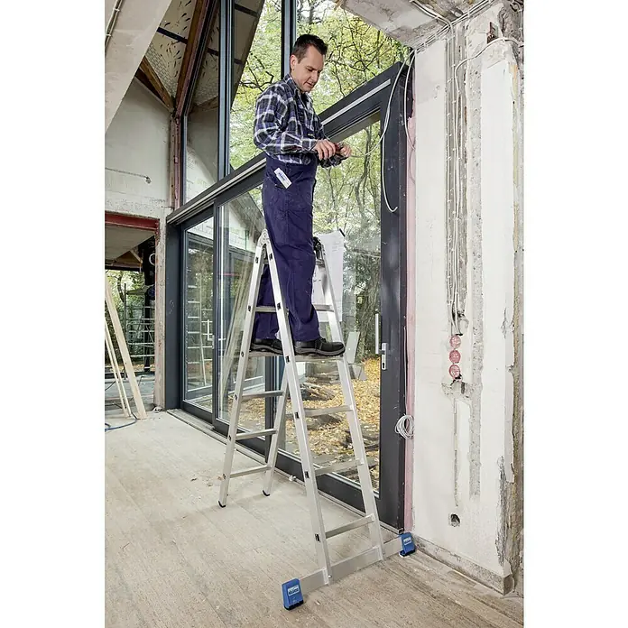 Krause Stabilo Doppelleiter - Anzahl Tritte: 12 Stk., Arbeitshöhe: 4,4 m, Aluminium - Ein Mann benutzt eine Klappleiter, um an einem Fenster zu arbeiten. Die Leiter ist aus Aluminium und hat blaue Füße.