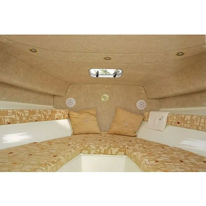 PEGAZUS GFK-Boot Escapade 600 Base SunTop - Max. 6 Personen, Nutzlast: 660 kg, CE-Klasse C - Innenraum einer Yacht mit beigen Polstern, Kissen und einer Luke, die natürliches Licht hereinlässt. Gemütlicher Kabinenbereich.