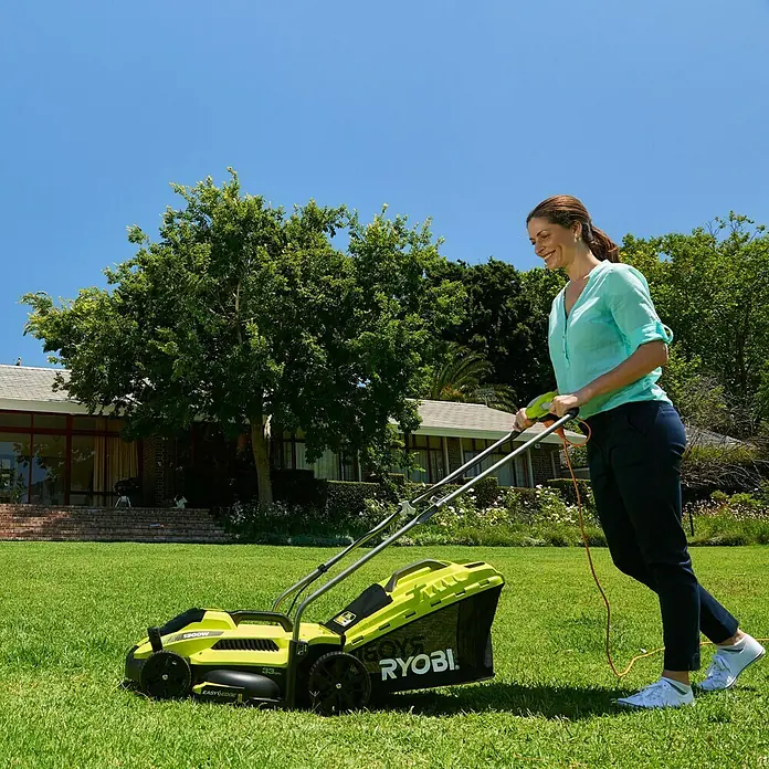 Ryobi Elektro-Rasenmäher RLM13E33S - 1.300 W, Schnittbreite: 33 cm - Frau benutzt Ryobi-Rasenmäher im Garten. Der Rasenmäher ist gelb und schwarz, das Gras ist grün.
