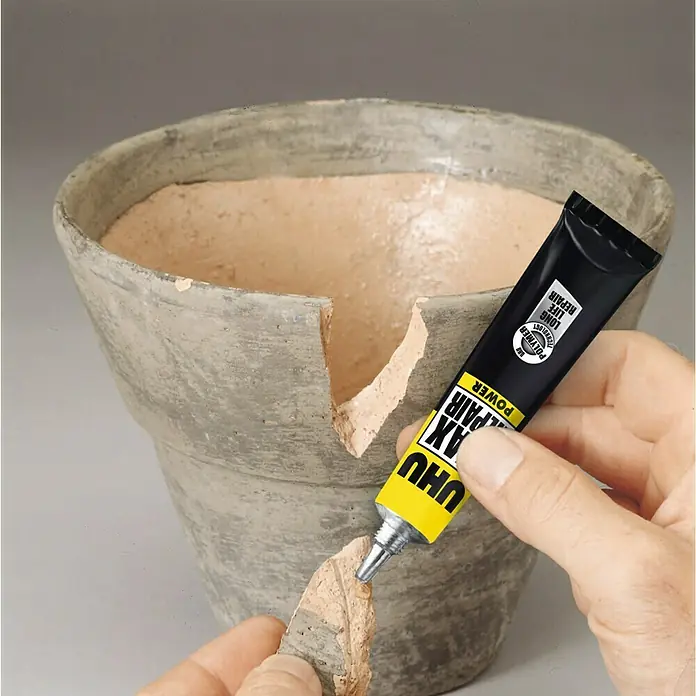 UHU Extrem-Kleber Max Repair - Transparent, 20 g, Tube - Ein Tube UHU 4x Repair Power Kleber wird verwendet, um eine zerbrochene Keramikvase zu reparieren. Der Kleber ist gelb-schwarz.