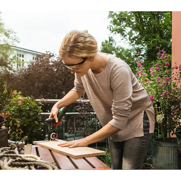 Bosch Power for All 12V NanoBlade-Säge EasyCut 12 - 12 V, Ohne Akku, Leerlaufdrehzahl: 4.100 U/min - Frau arbeitet im Freien mit einem Bosch Multifunktionswerkzeug an einem Holzbrett.