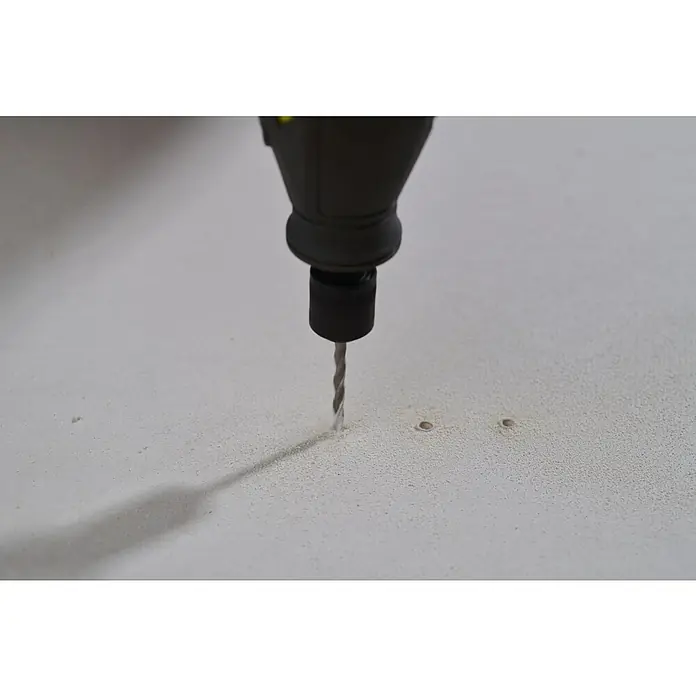 Ryobi Trockenbau-Bohrersatz RAR402-8 - Durchmesser Schaft: 3,2 mm, 8 Stk. - Bohrmaschine bohrt ein Loch in eine weiße Oberfläche, wobei der Fokus auf der Präzision des Werkzeugs liegt. Staubpartikel sind sichtbar.