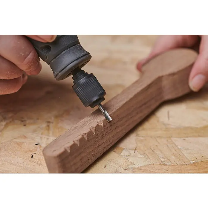Ryobi Fräsmesser RAR106 rechtecklig-gerillt - Passend für: Rotationswerkzeuge mit 3,2 mm (1/8") Spannzangenkapazität - Nahaufnahme eines Dremel-Werkzeugs, das zum Formen eines Holzlöffels verwendet wird, wobei der Fokus auf dem Präzisionsschleifen des Holzes liegt.