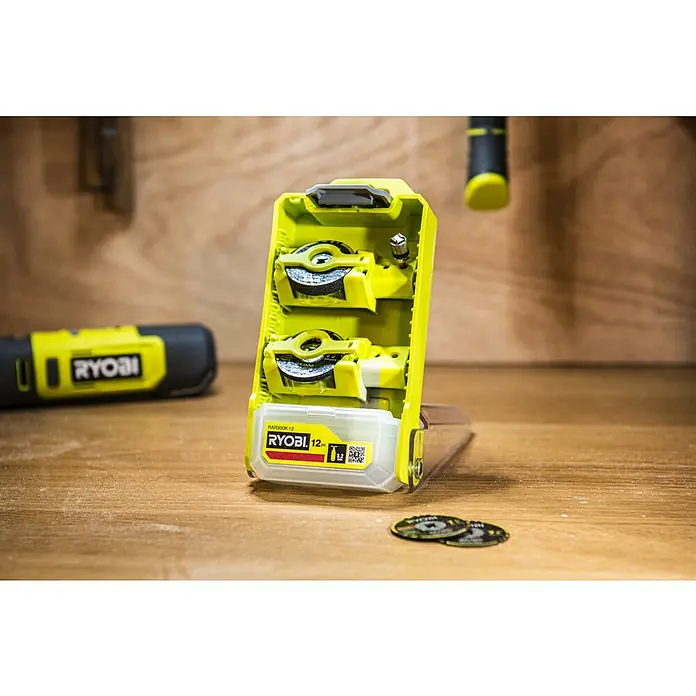 Ryobi Trennscheiben-Set "Twist Lock" RAR300K-12 - Durchmesser: 38 mm - Nahaufnahme des Ryobi RAR300K-12 Trennscheibensatzes in gelber Aufbewahrungsbox auf einer Holzoberfläche.