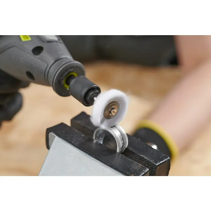 Ryobi Polierscheiben RAR201 - Durchmesser: 25,4 mm, Passend für: Alle Rotationswerkzeuge mit 3,2 mm (1/8") Spannzangenkapazität - Ein Elektrowerkzeug mit Polieraufsatz bearbeitet einen Metallring, der in einem Schraubstock fixiert ist, ideal für Metallbearbeitung.