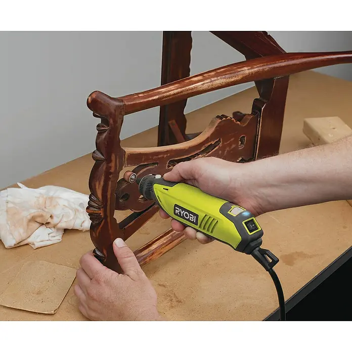 Ryobi Rotationswerkzeug-Set EHT150V - 150 W, 10.000 U/min - 35.000 U/min - Detailaufnahme eines Ryobi-Elektrowerkzeugs, das zum Schleifen eines Holzstuhls verwendet wird. Das Gerät ermöglicht präzises und müheloses Arbeiten.