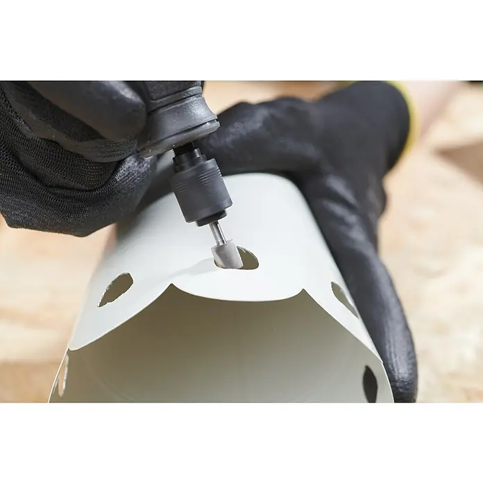 Ryobi Fräsmesser RAR104 zylindrisch - Arbeitsdurchmesser: 8 mm, Passend für: Rotationswerkzeuge mit 3,2 mm (1/8") Spannzangenkapazität - Nahaufnahme einer Person, die mit einem Dremel ein Loch in ein weißes PVC-Rohr schneidet, wobei schwarze Handschuhe getragen werden.