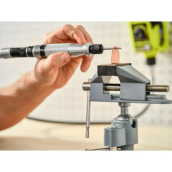 Ryobi Bohrersatz RAR401-7 - 7 -tlg. - Detailaufnahme einer Ryobi Schleifmaschine beim Gravieren eines Schmuckstücks, das in einem Schraubstock befestigt ist. Präzise Arbeit für Schmuckdesign.