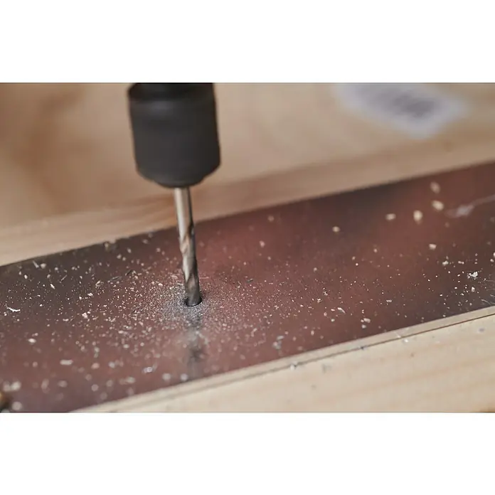 Ryobi Bohrersatz RAR401-7 - 7 -tlg. - Nahaufnahme einer Bohrmaschine beim Bohren eines Lochs in ein Metallstück, wobei Metallspäne entstehen.