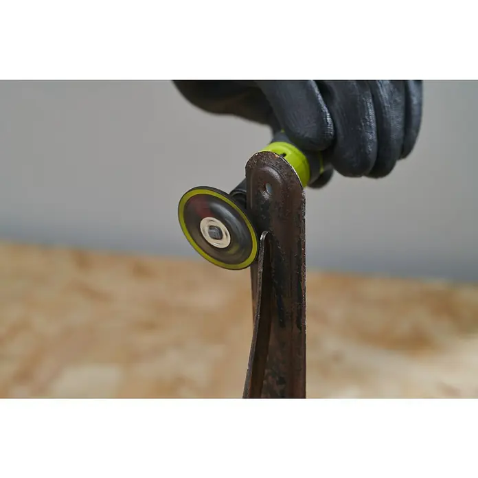Ryobi Schleifscheiben RAR507-2 - Passend für: Rotationswerkzeuge mit 3,2 mm (1/8") Spannzangenkapazität - Ein Handwerker schleift mit einer Mini-Trennschleifmaschine ein Stück Metall, wobei der grüne Griff des Werkzeugs und die Schutzhandschuhe sichtbar sind.