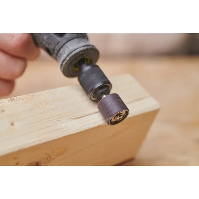 Ryobi Schleifband-Set RAR602-10 - Körnung: 120 - Nahaufnahme eines Dremel-Rotationswerkzeugs, das eine Schleifhülse verwendet, um ein Stück Holz zu schleifen, um eine glatte Oberfläche zu erhalten.