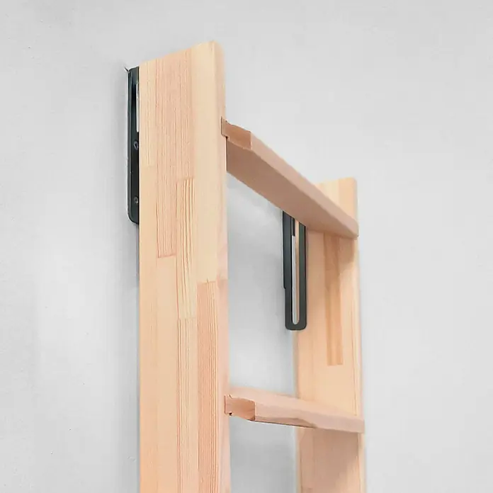 Dolle Schiebebeschlag - Schwarz, Passend für: Dolle Hochbettleitern - Nahaufnahme eines hellen Holzregals mit schwarzen Metallhalterungen an einer weißen Wand befestigt.