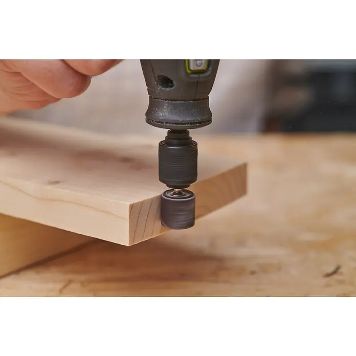 Ryobi Schleifband-Set RAR603-10Körnung: 240 - Nahaufnahme eines Dremel-Rotationswerkzeugs mit Schleifband, das eine Holzkante bearbeitet, ideal für feine Detailarbeiten und Holzbearbeitungsprojekte.