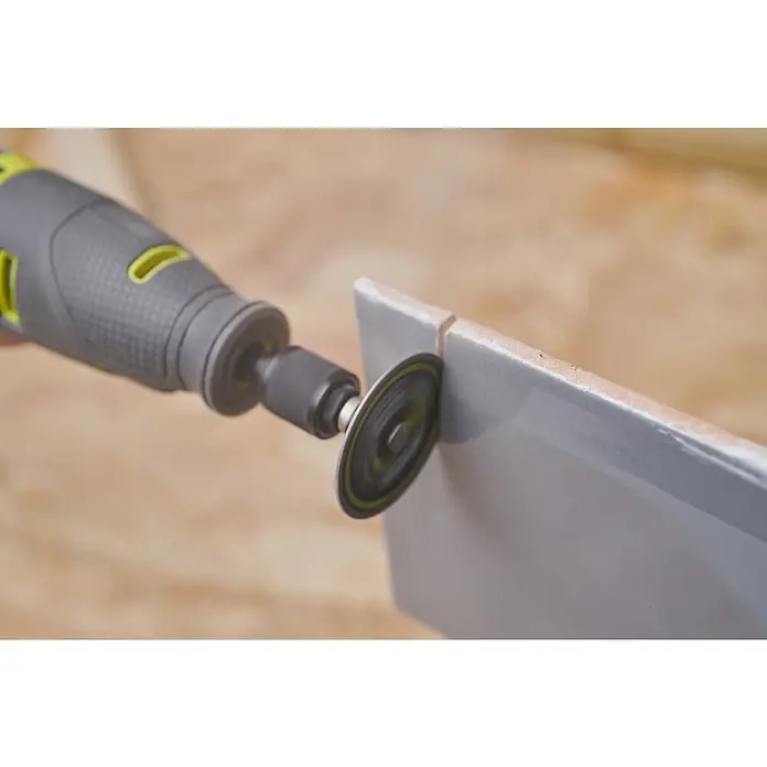 Ryobi Diamant-Trennscheibe RAR305 Twist-Lock - Durchmesser Scheibe: 38 mm, Passend für: Rotationswerkzeuge mit 3,2 mm (1/8") Spannzangenkapazität - Nahaufnahme eines Multifunktionswerkzeugs beim Schleifen einer Fliese. Das Werkzeug ist grau und hat einen grünen Akzent, mit einer Schleifscheibe am Ende.